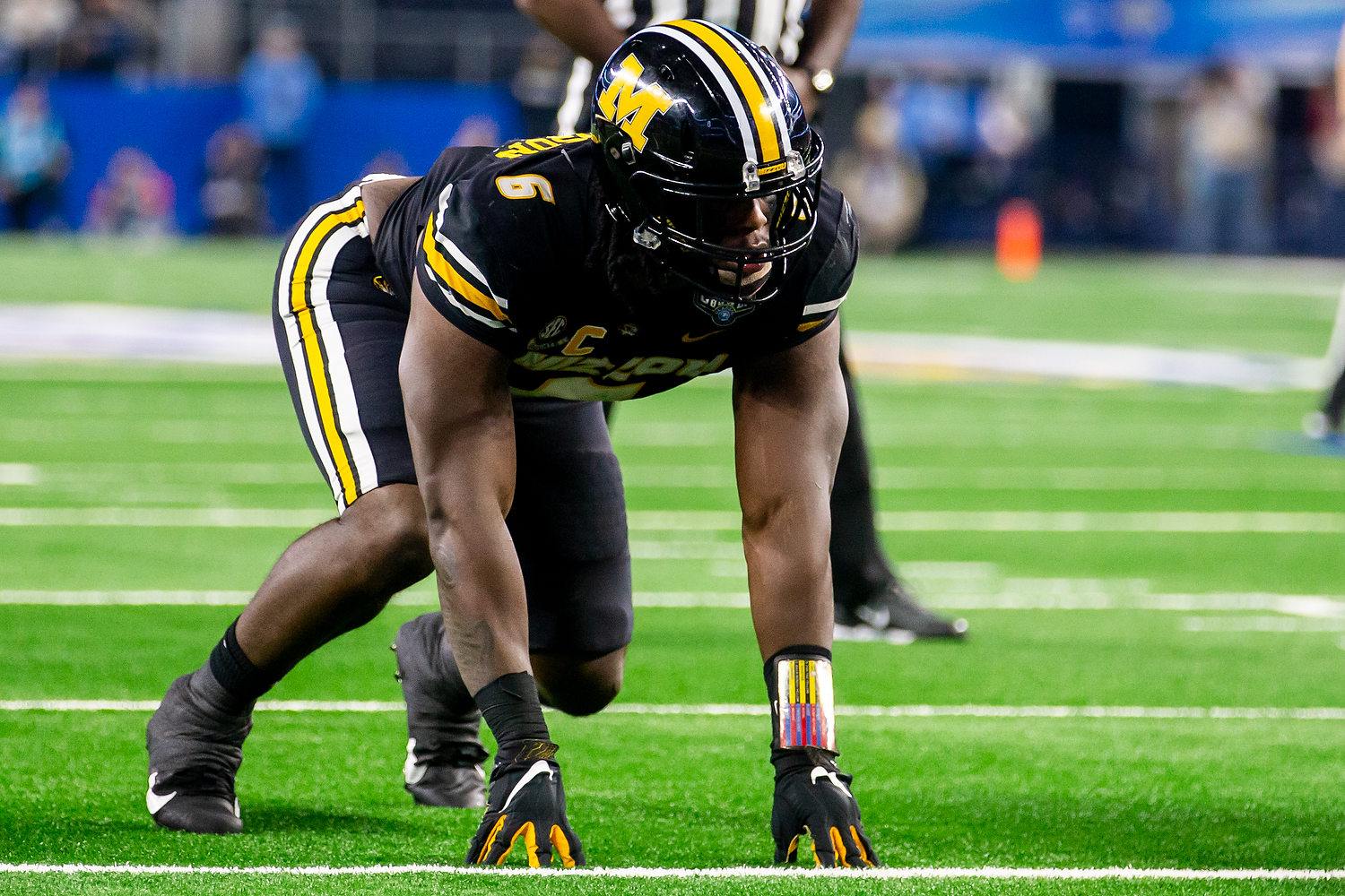 Football player in uniform crouched on field in ready stance