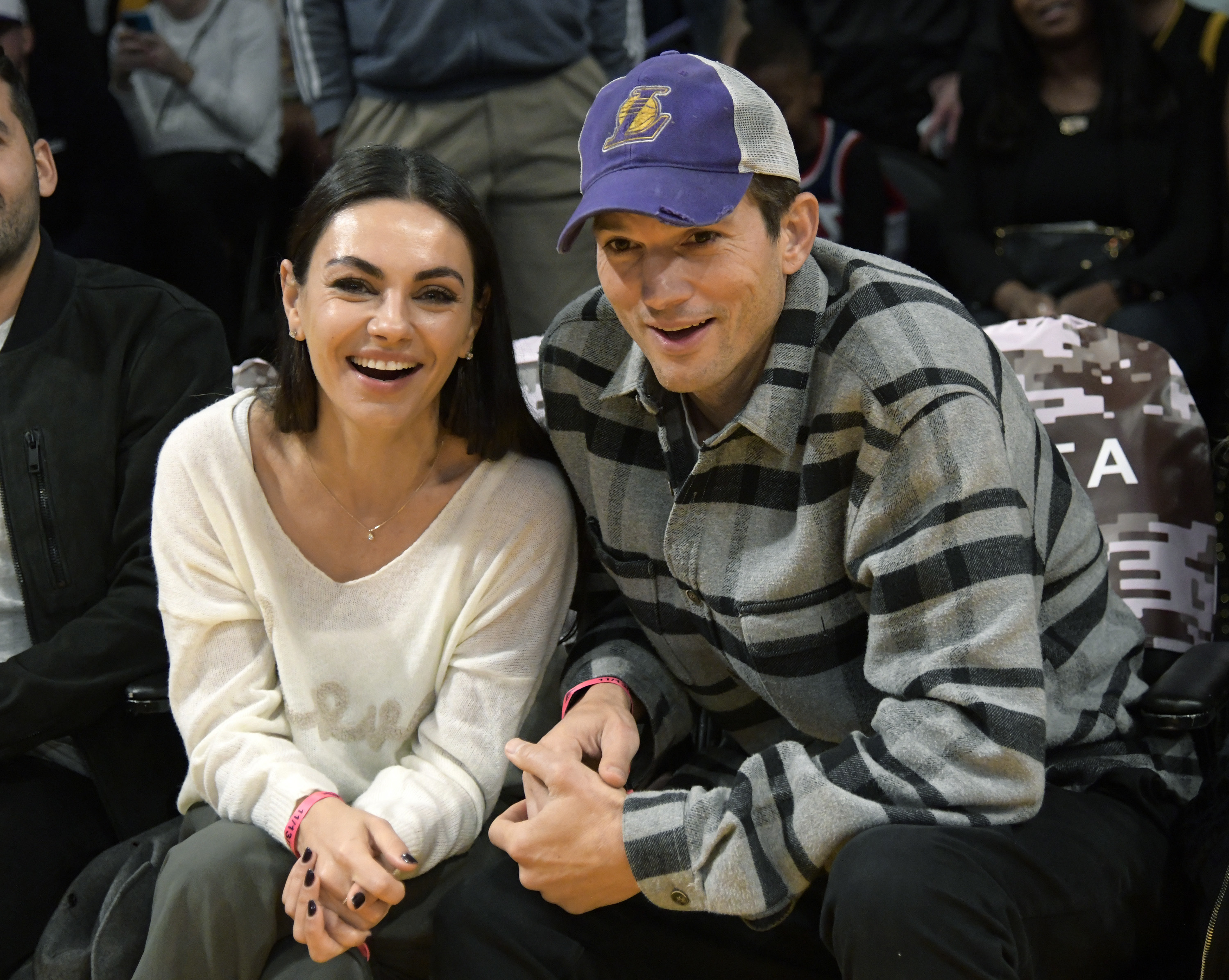 Mila Kunis and Ashton Kutcher sitting courtside at a basketball game