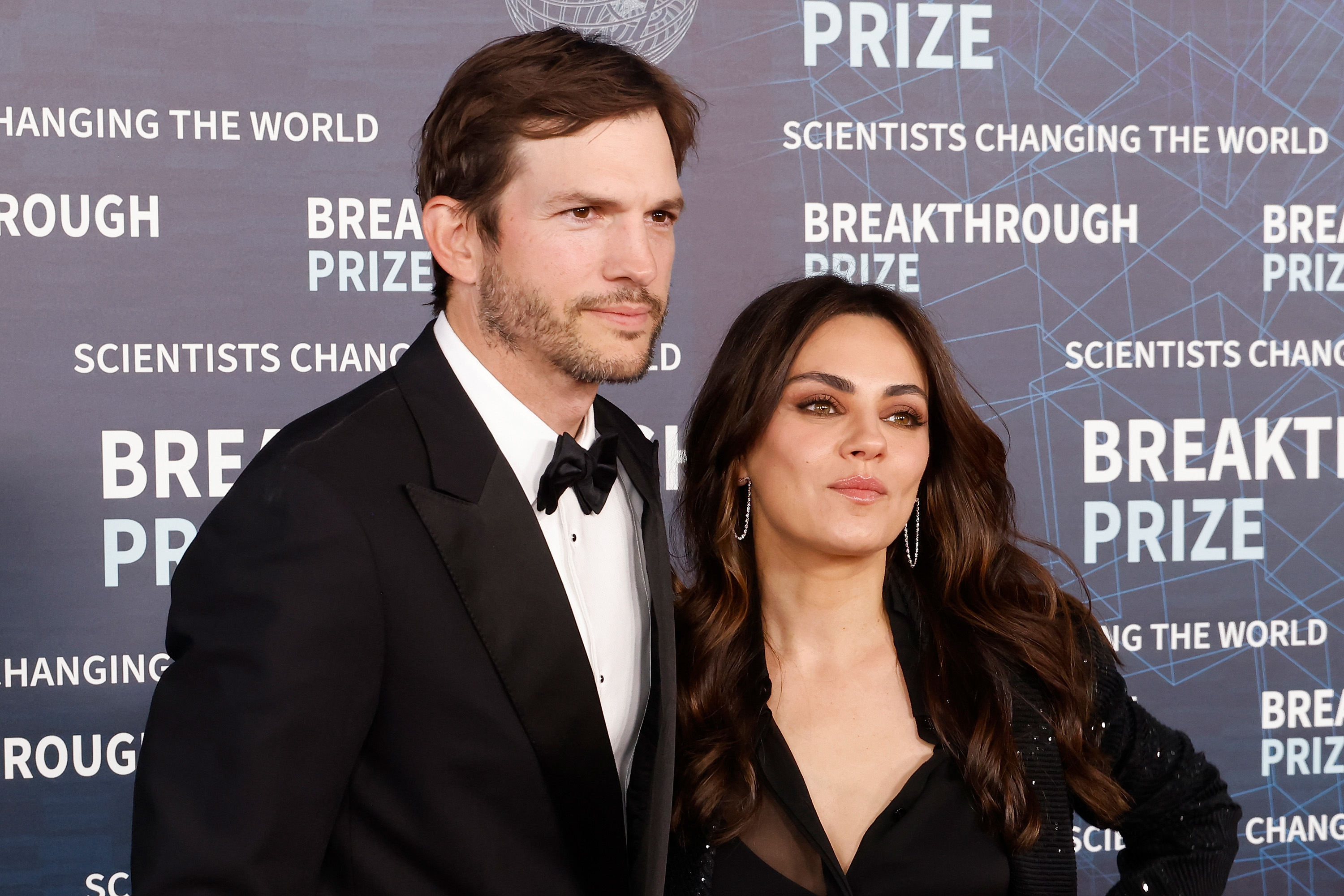 Closeup of Ashton Kutcher and Mila Kunis posing on the red carpet together