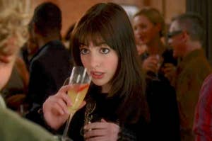 Anne Hathaway holding a drink to her lips as Andy in The Devil Wears Prada