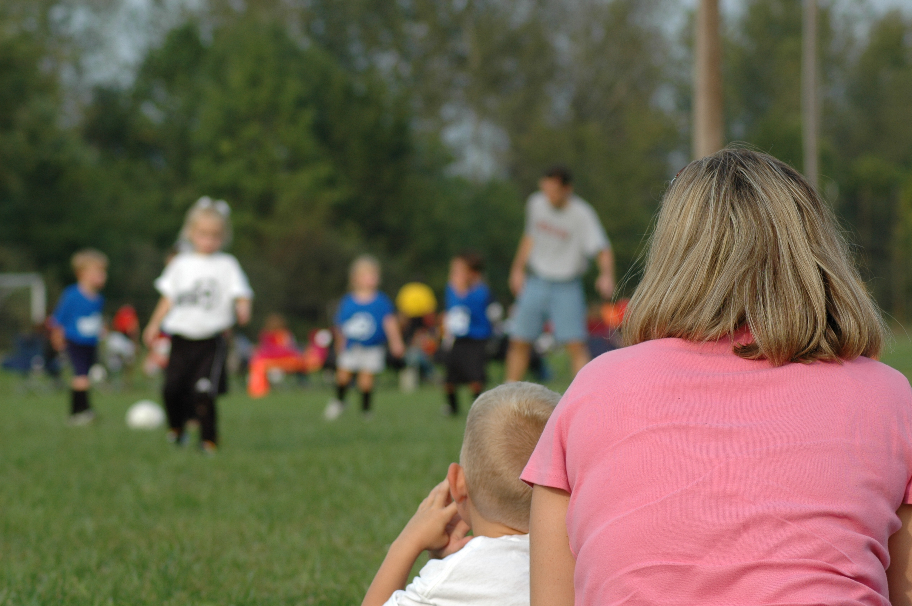 Parent and child watching kids play soccer on a field