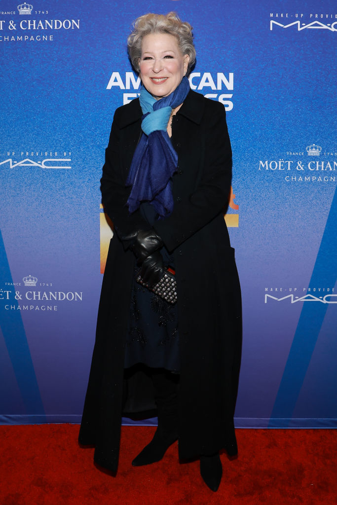 Bette Midler at an event wearing a coat, scarf, and gloves