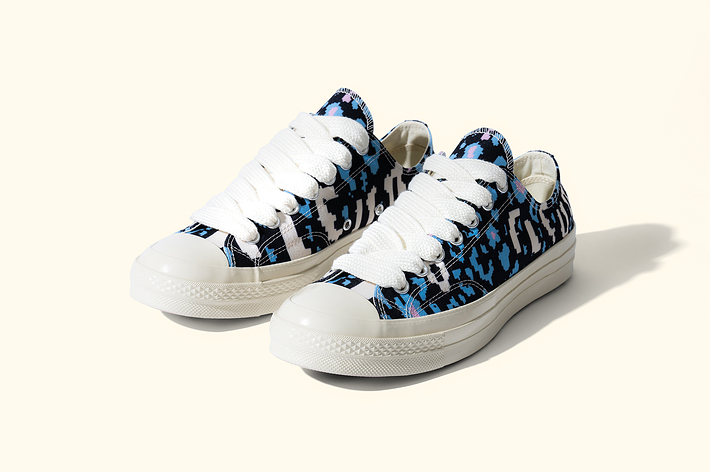 A pair of low-top sneakers with a unique black and blue pattern on a light background