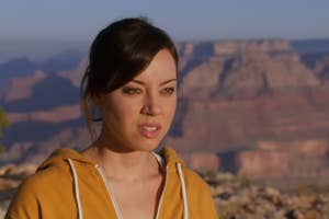 Aubrey Plaza in a hoodie standing before a canyon landscape.