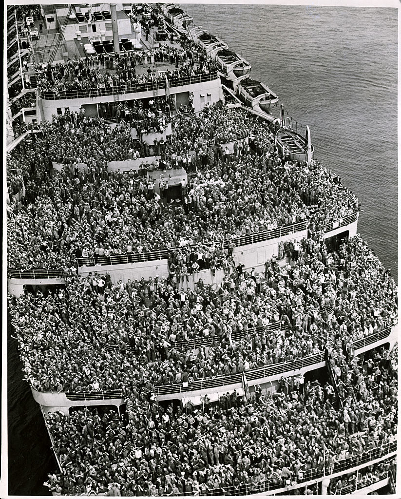 A historical photo of a ship&#x27;s deck crowded with passengers
