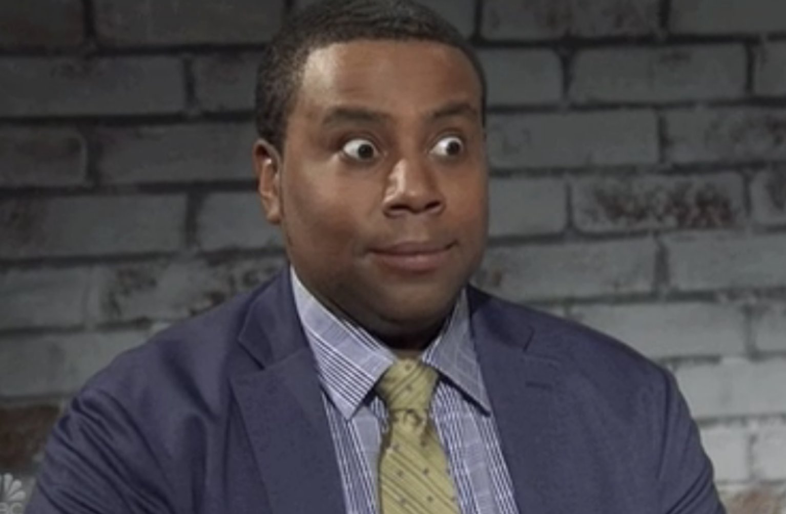 Kenan Thompson making a facial expression, wearing a suit and tie