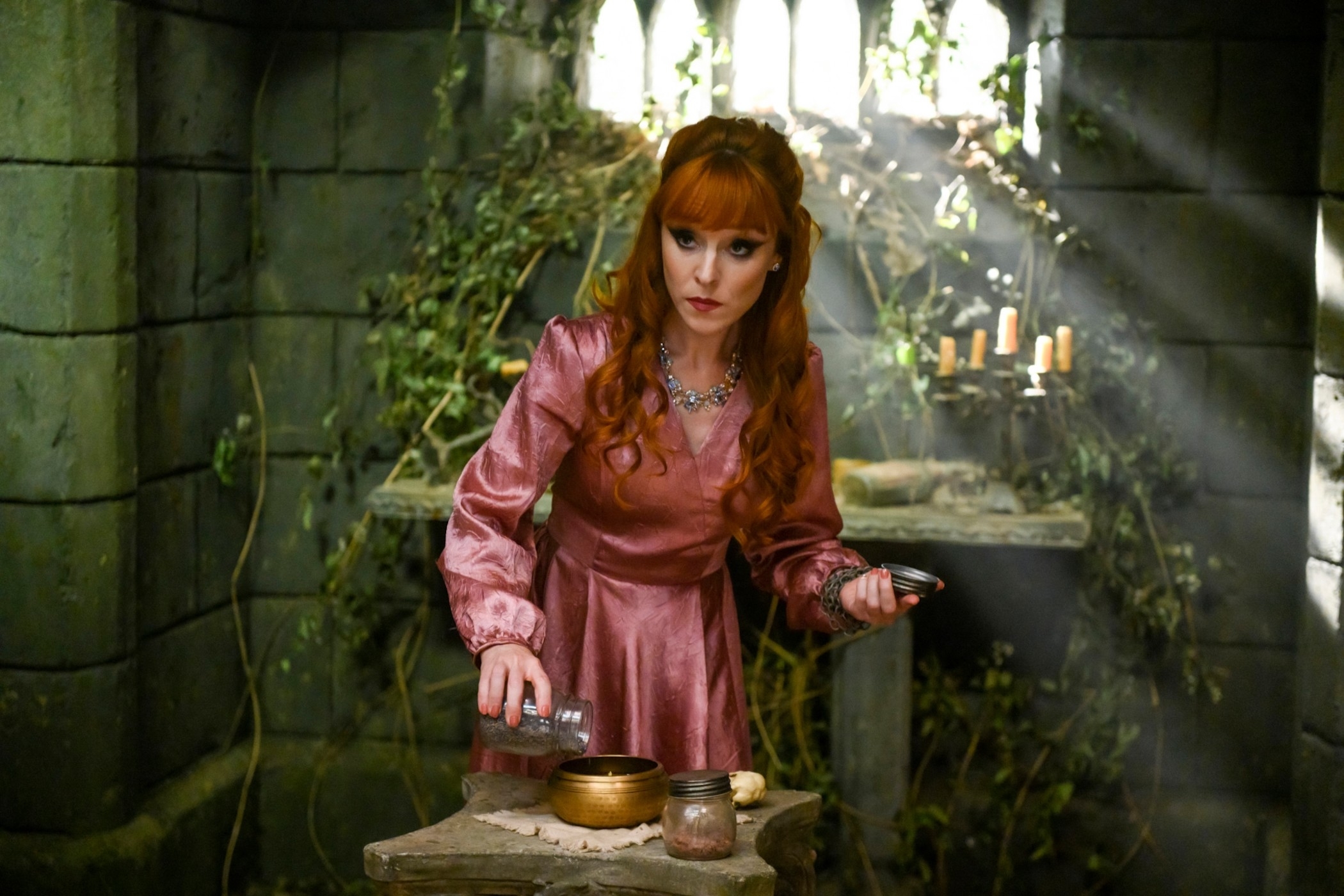 Elsa from Frozen in a satin dress, gesturing at a table with mystical props in an enchanted forest setting