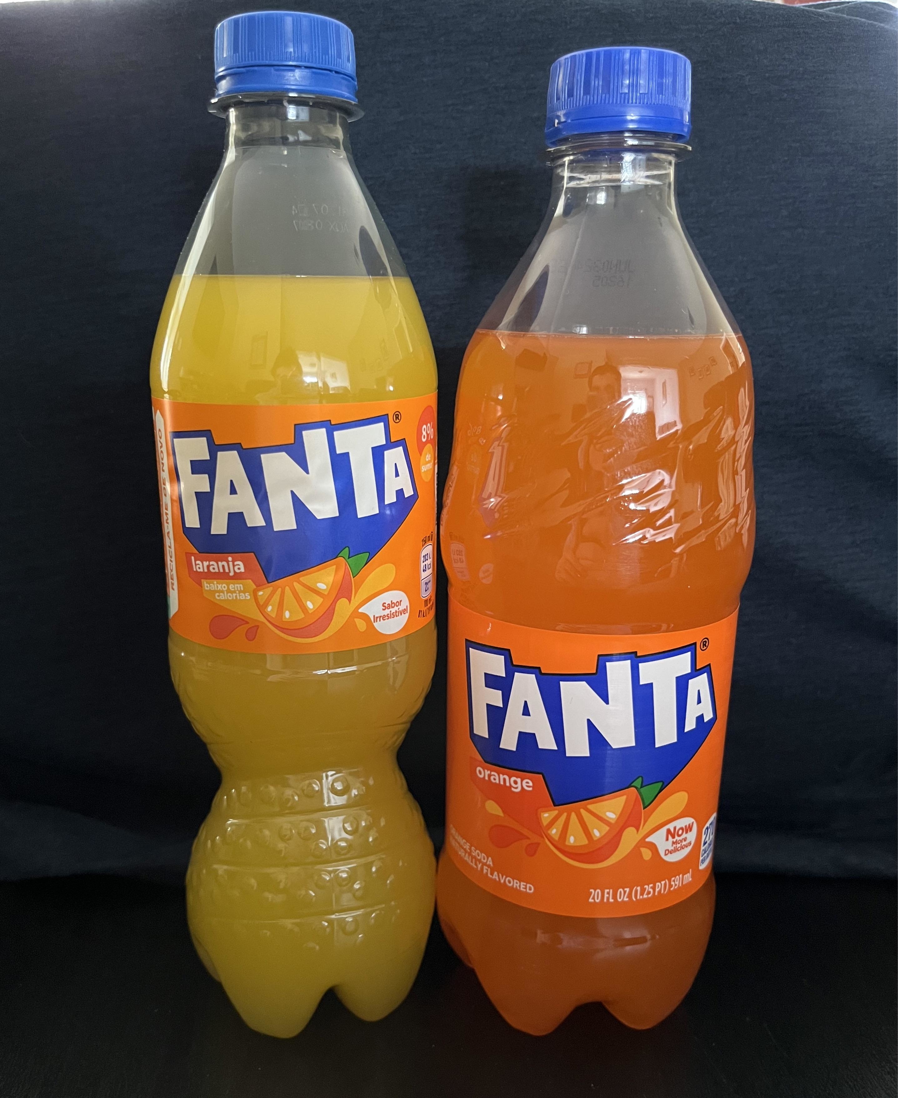 Two bottles of Fanta, one labeled Taranja and the other Orange, side by side against a black backdrop