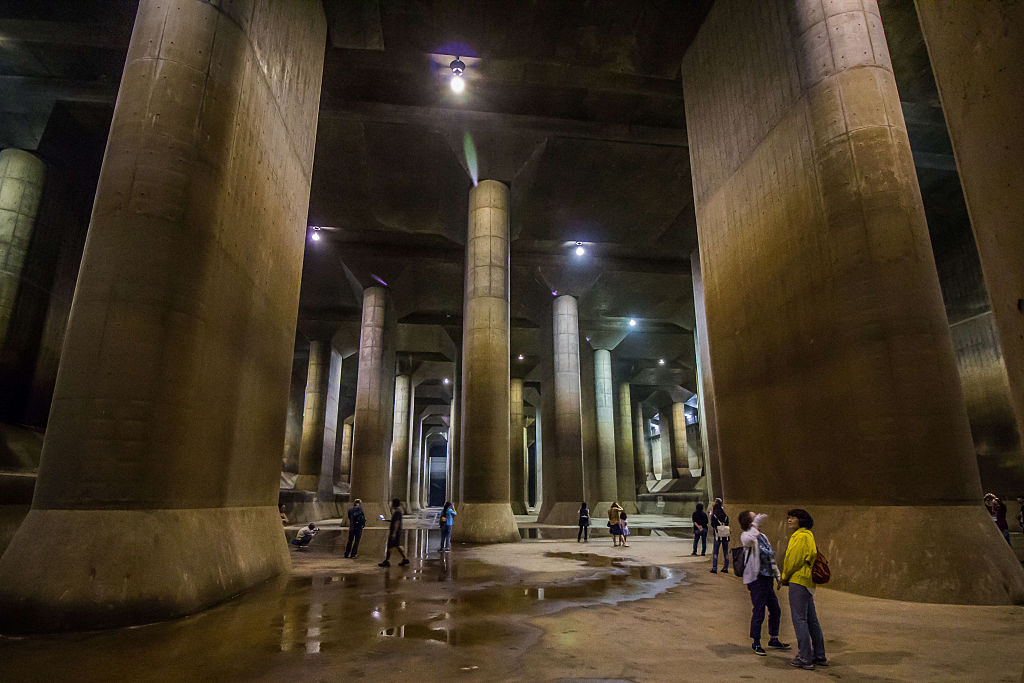 Interior of massive underground cistern with towering pillars and people exploring