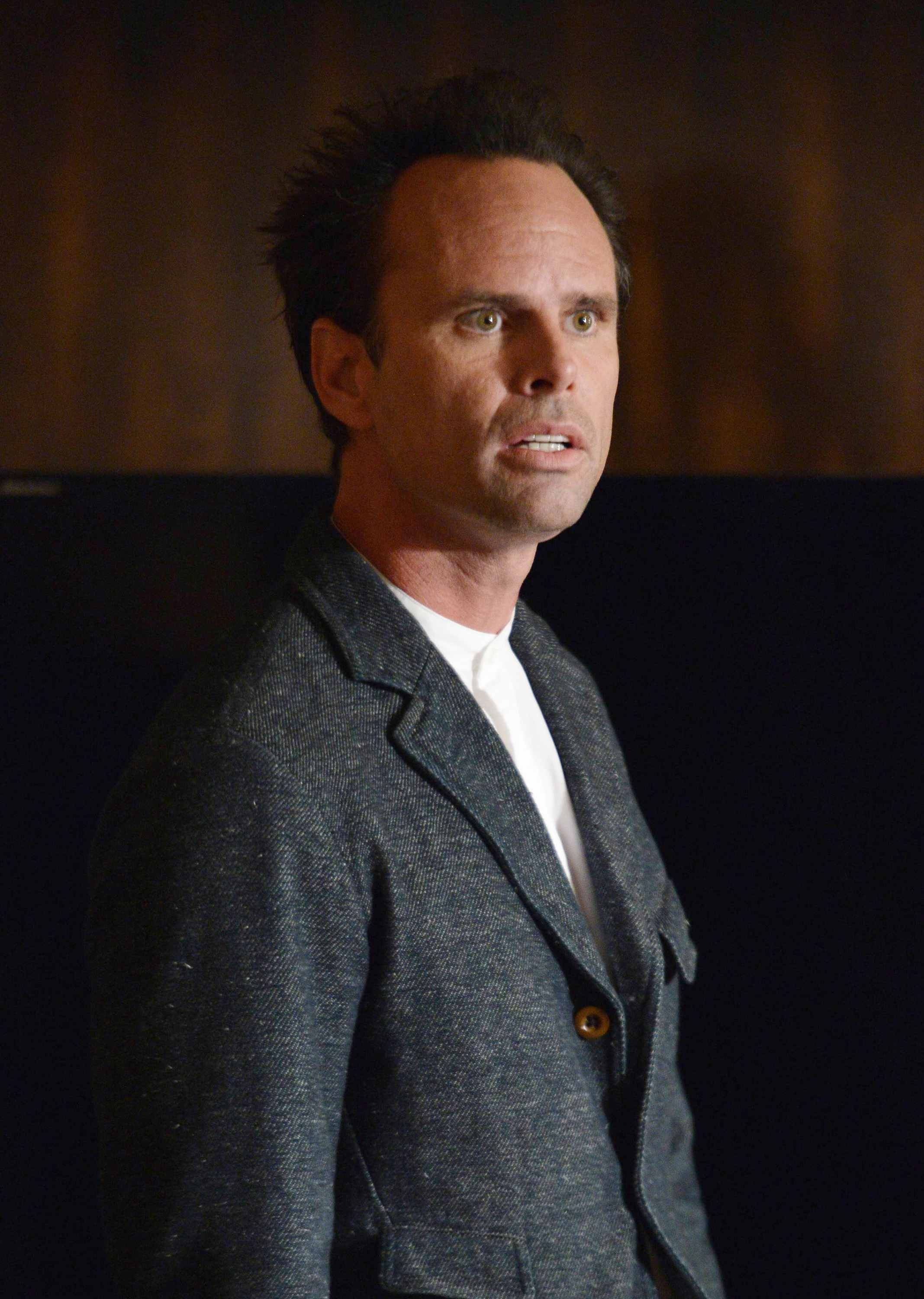 Walton Goggins standing in a suit jacket, looking to the side with an intense expression