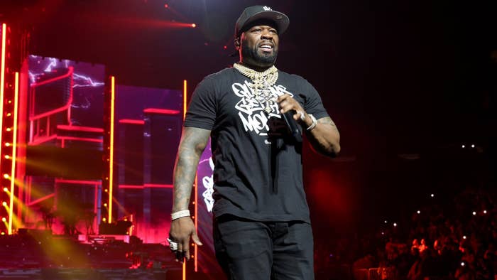 50 Cent performing on stage wearing a graphic t-shirt and gold necklaces