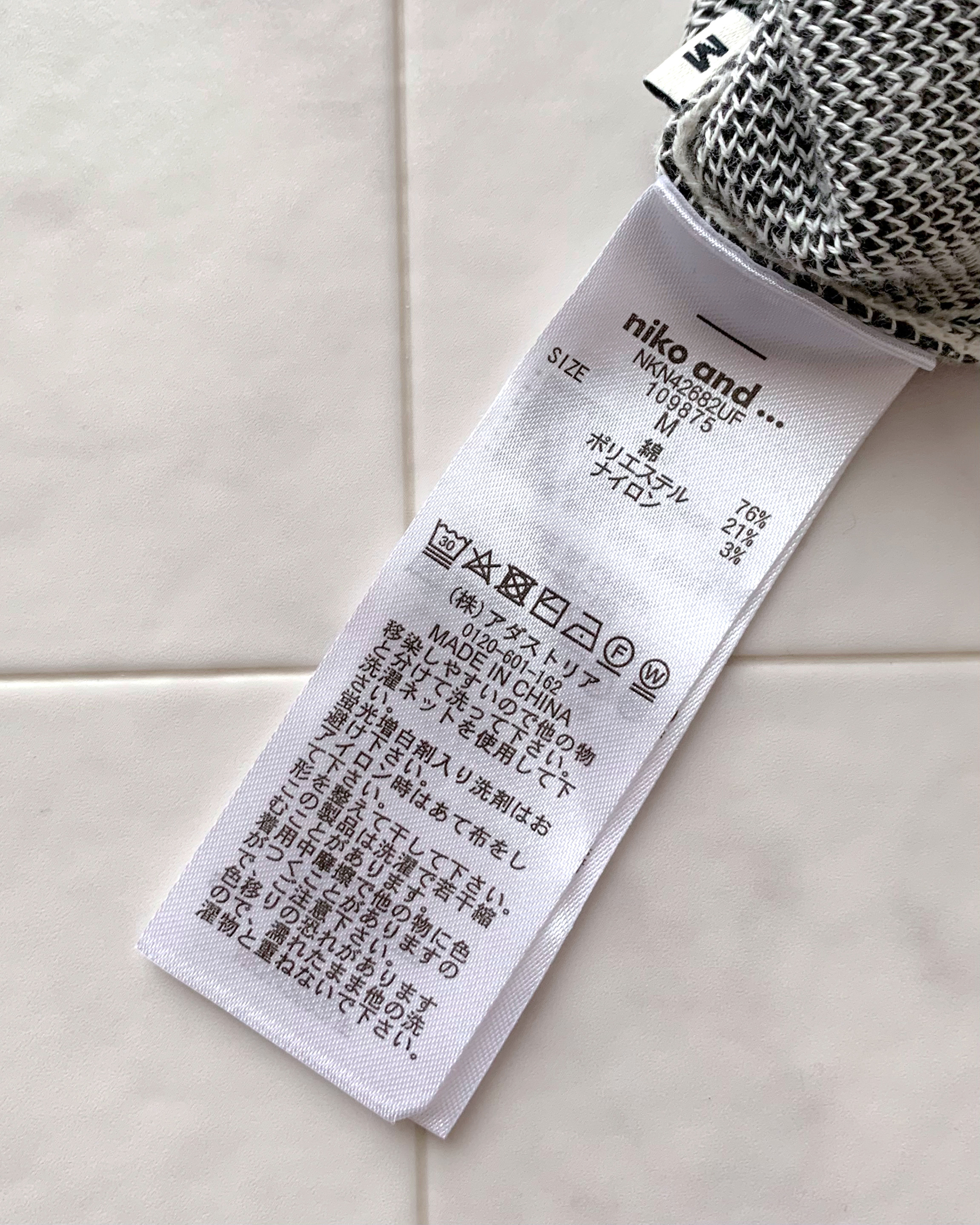 Clothing label with washing instructions and symbols, brand 'niko and…' visible, in English and Japanese
