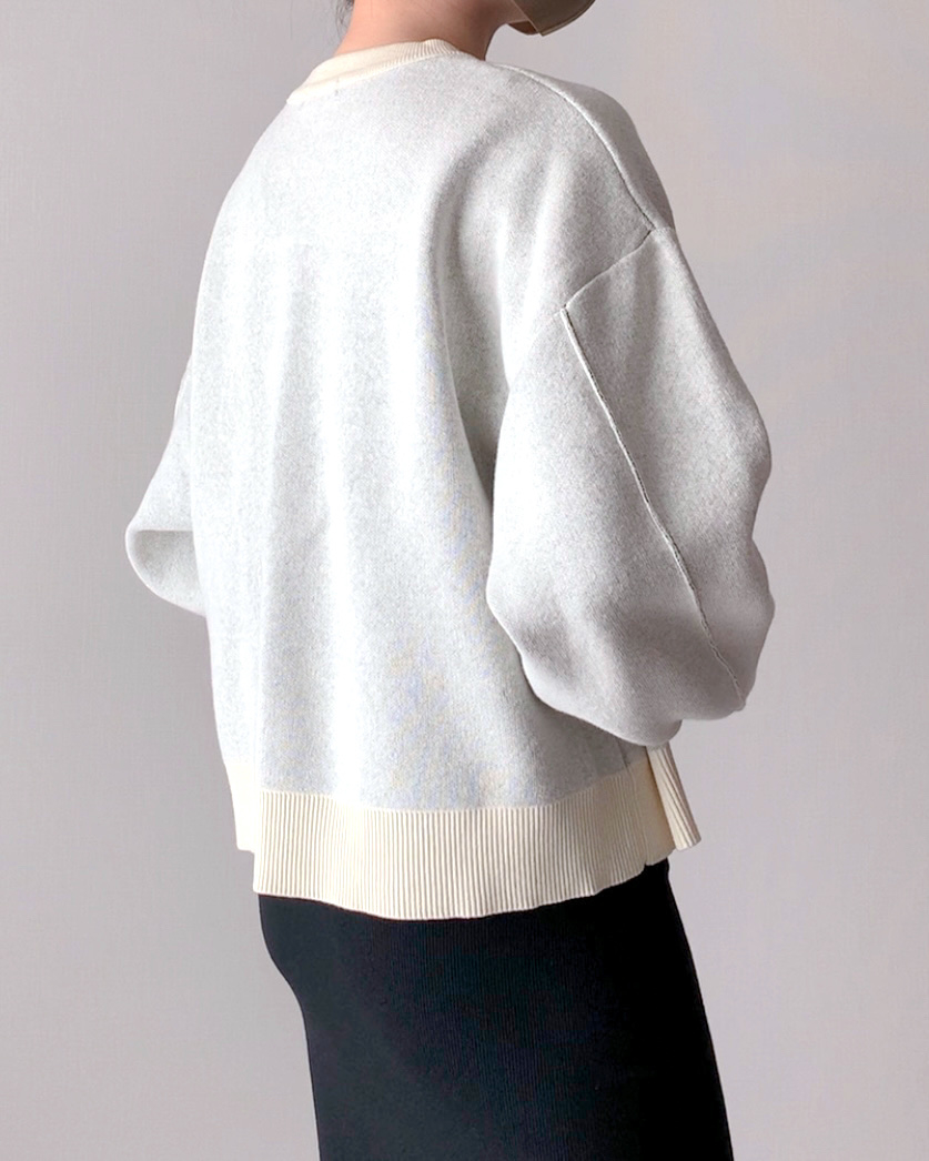Person in a white sweater with puffy sleeves, viewed from the back