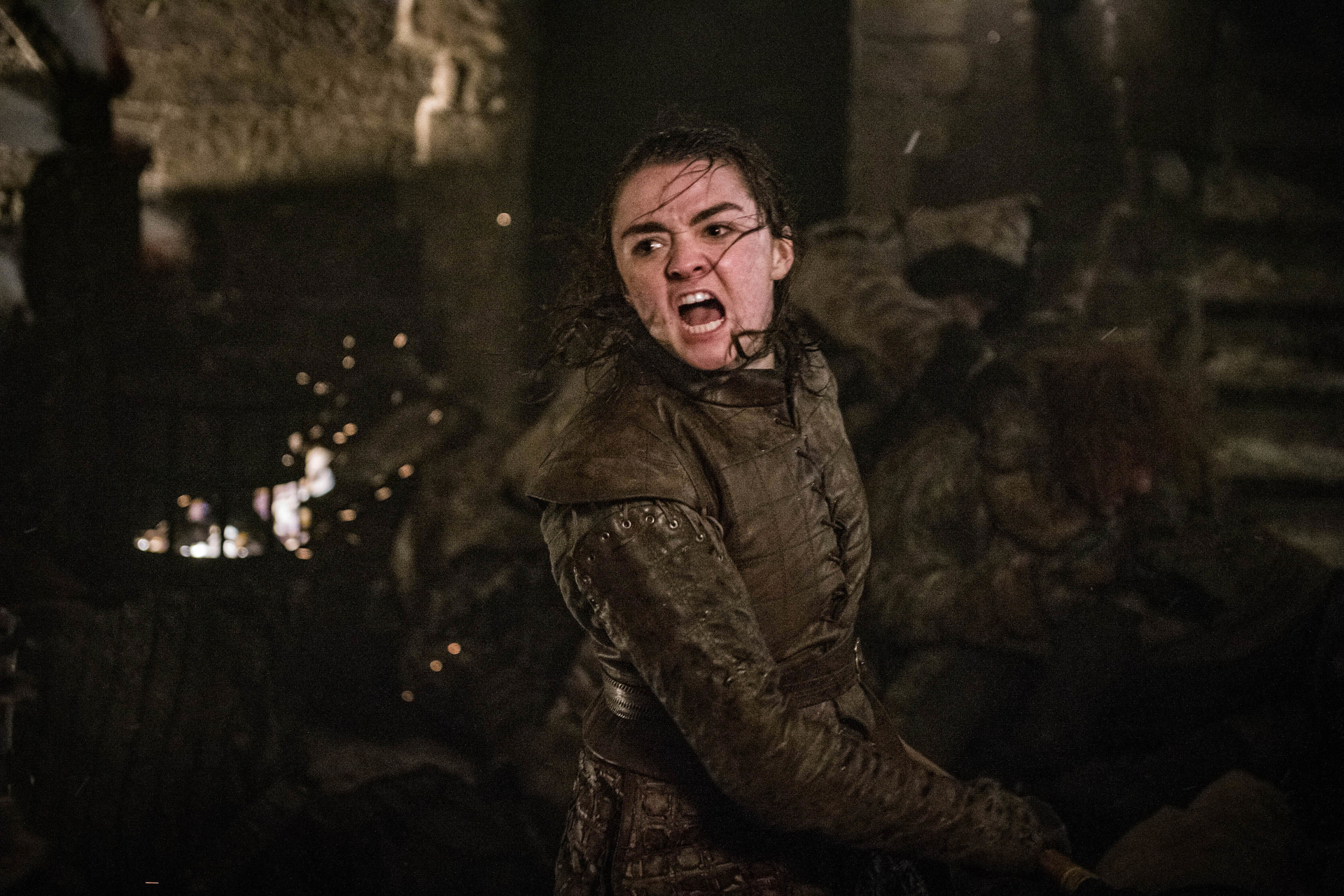 Maisie Williams as Arya Stark in an intense scene with a battle backdrop