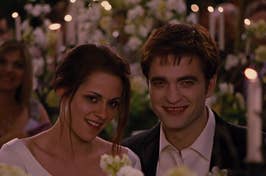 Bella and Edward from Twilight smiling at their wedding. Edward in a tuxedo, Bella in a wedding dress