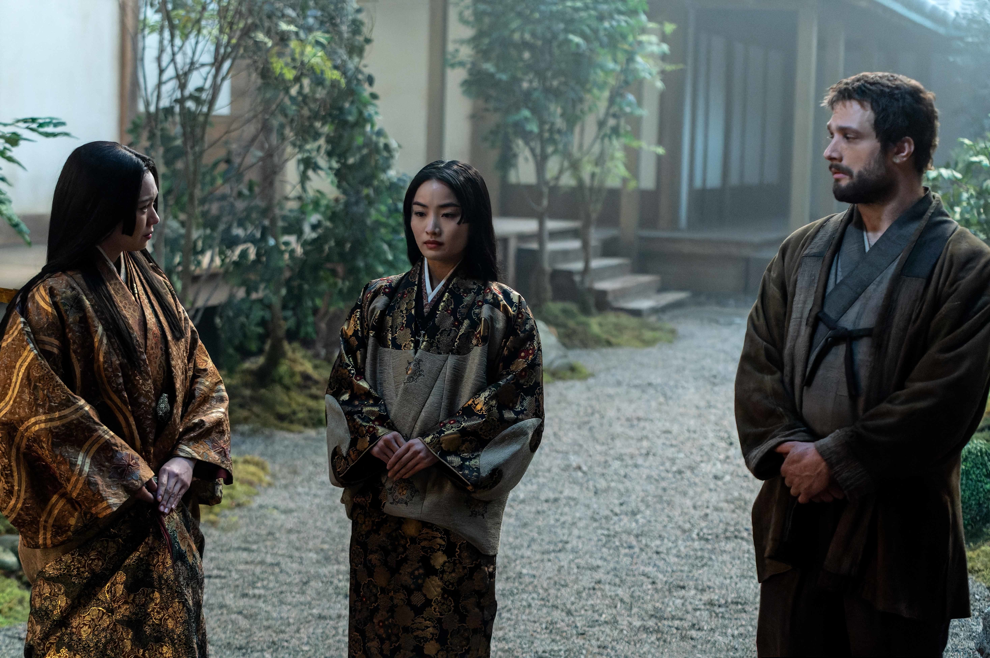 Three actors standing in a traditional Japanese setting, wearing kimonos; two women and one man