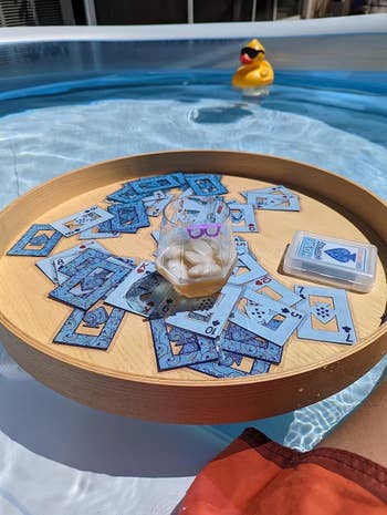 Playing cards scattered connected a woody tray successful a pool, with a rubber duck nearby