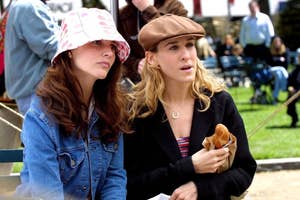 Charlotte in a pink bucket hat, Carrie in a brown beret, both engaged in conversation while sitting on a park bench.