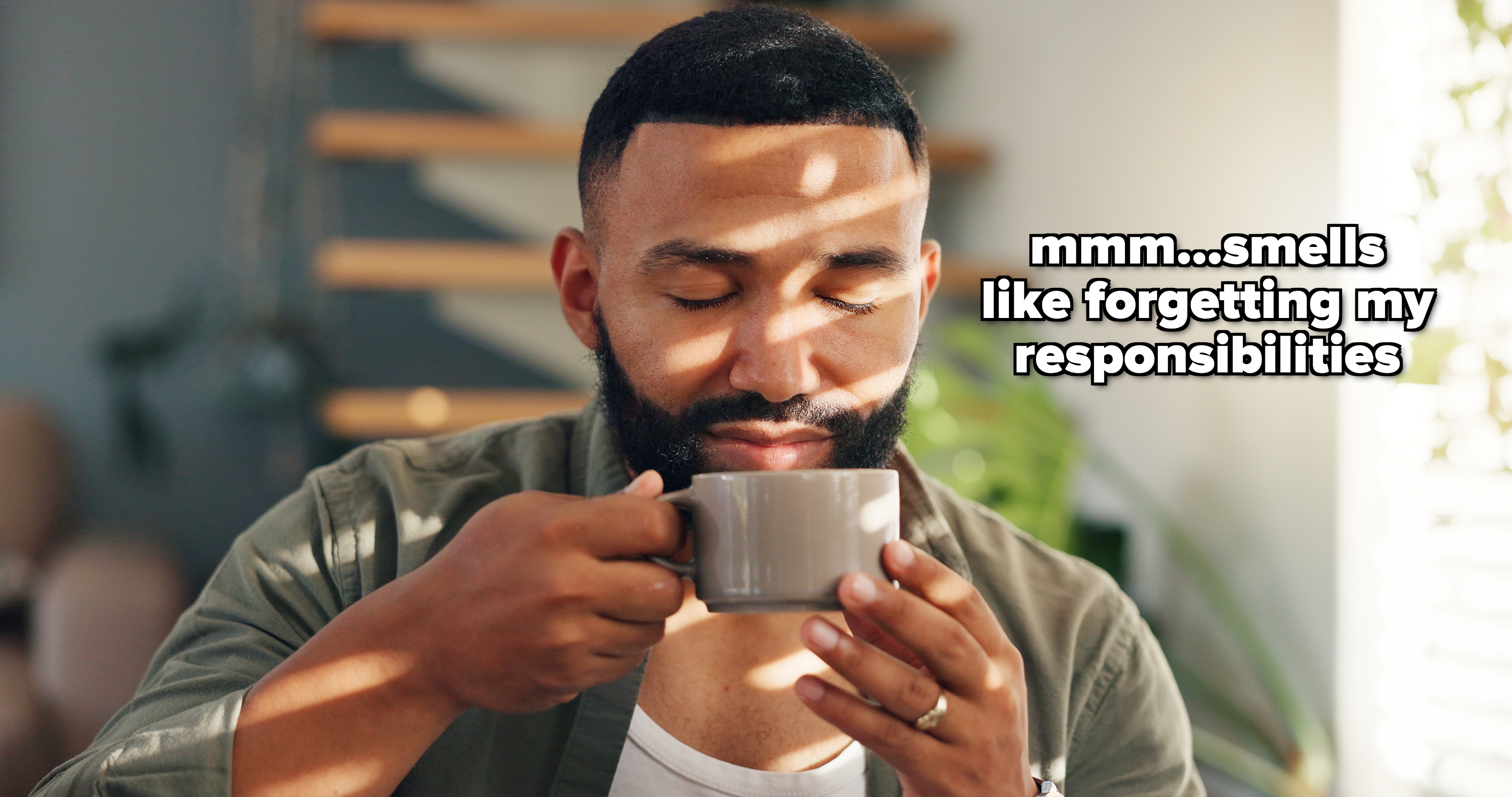 Man with a beard enjoying a cup of coffee with his eyes closed, indoors