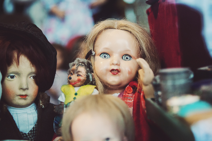 Vintage dolls displayed, focus on one with blue eyes and red outfit. No persons to name