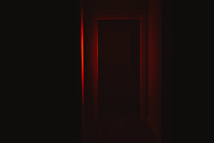 A dimly lit corridor with an illuminated exit sign at the far end