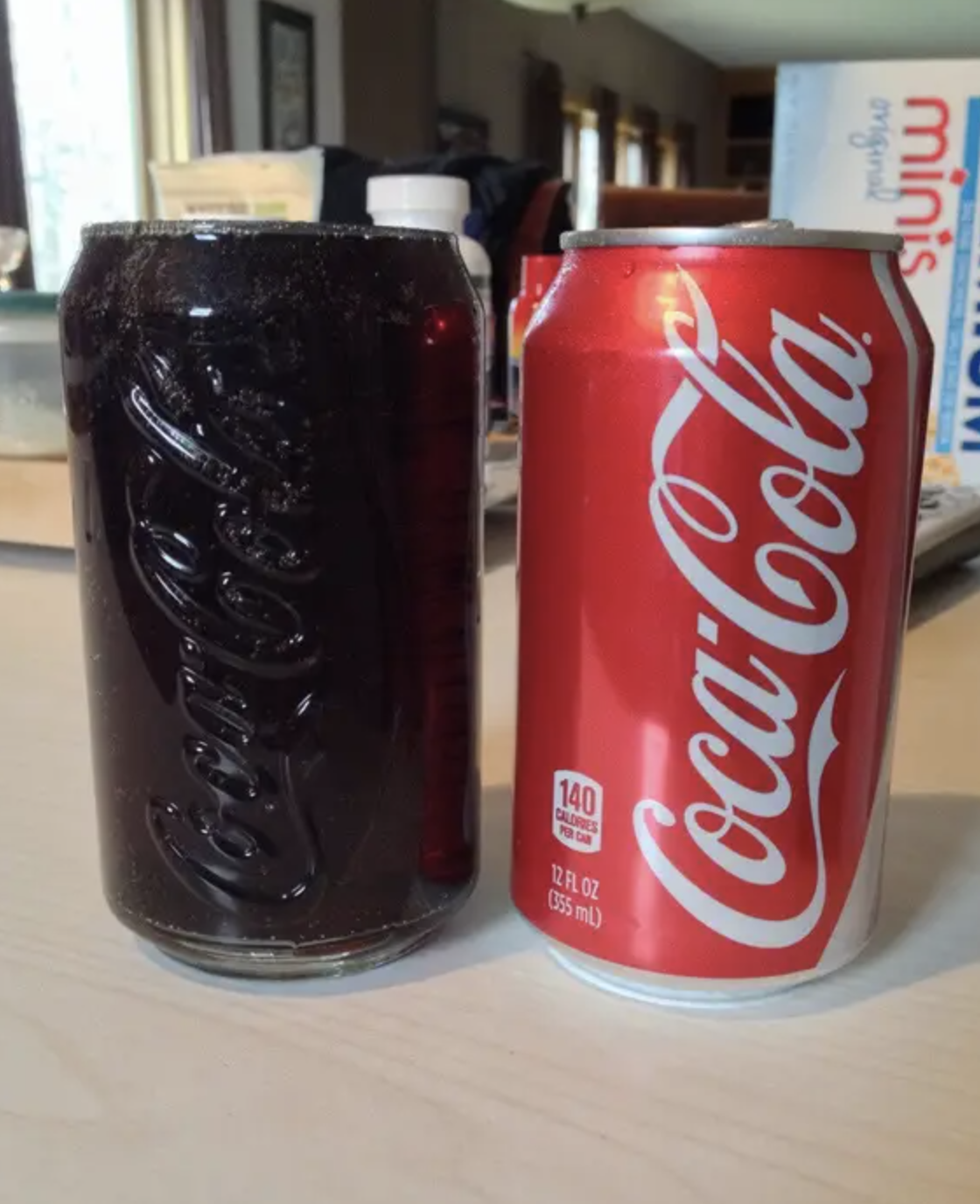 A Coke can beside a clear glass with a dark fizzy beverage, possibly Coke, with no individuals in the image