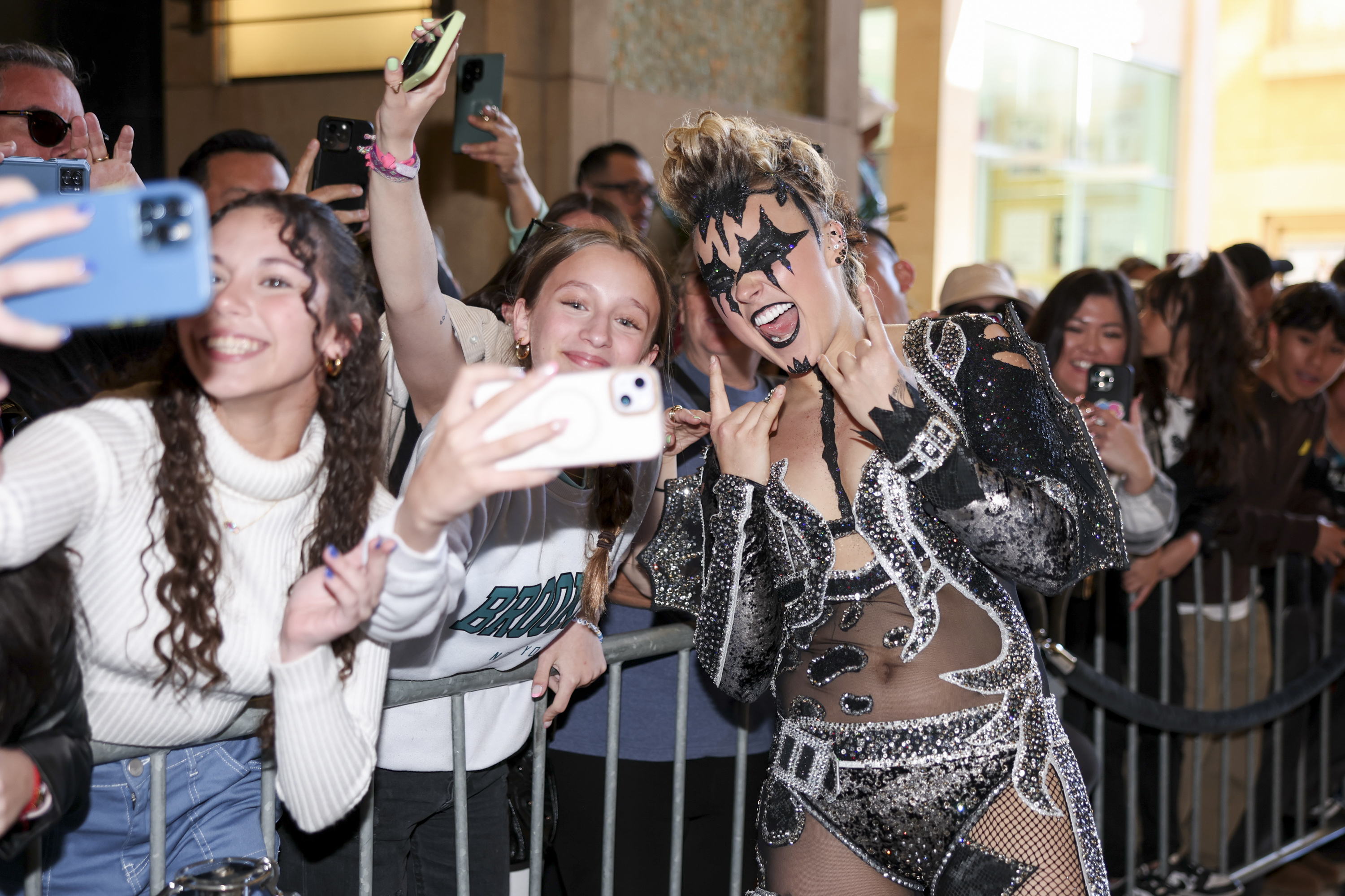 Fans take selfies with a celebrity wearing a sparkling bodysuit with bold cutouts at an event