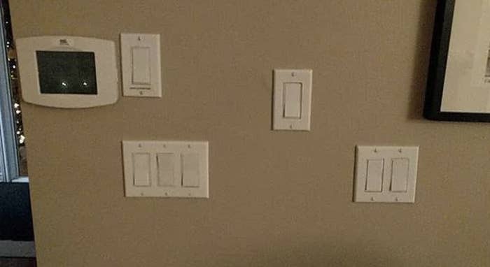 Five light switches on a wall, with various button configurations, and a framed picture to the right