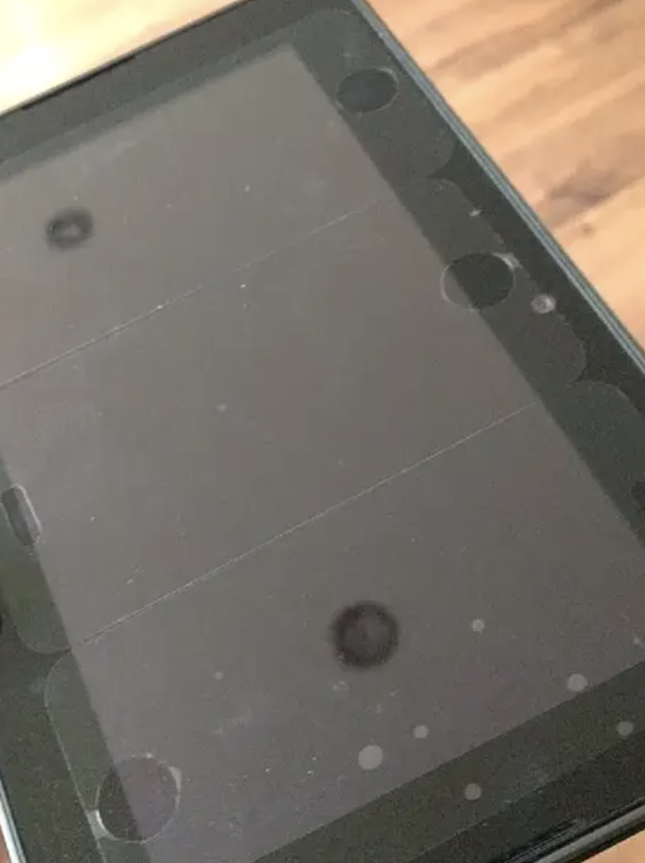 BlackBerry smartphone held in hand with screen off, displaying reflections
