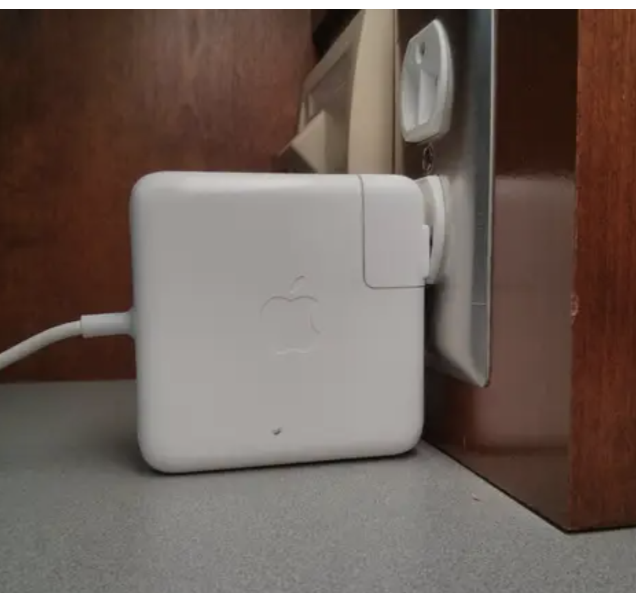 Apple charger plugged into a wall outlet with cable attached