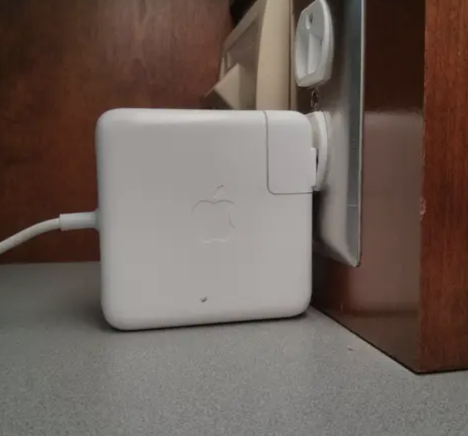 Apple charger plugged into a wall outlet with cable attached
