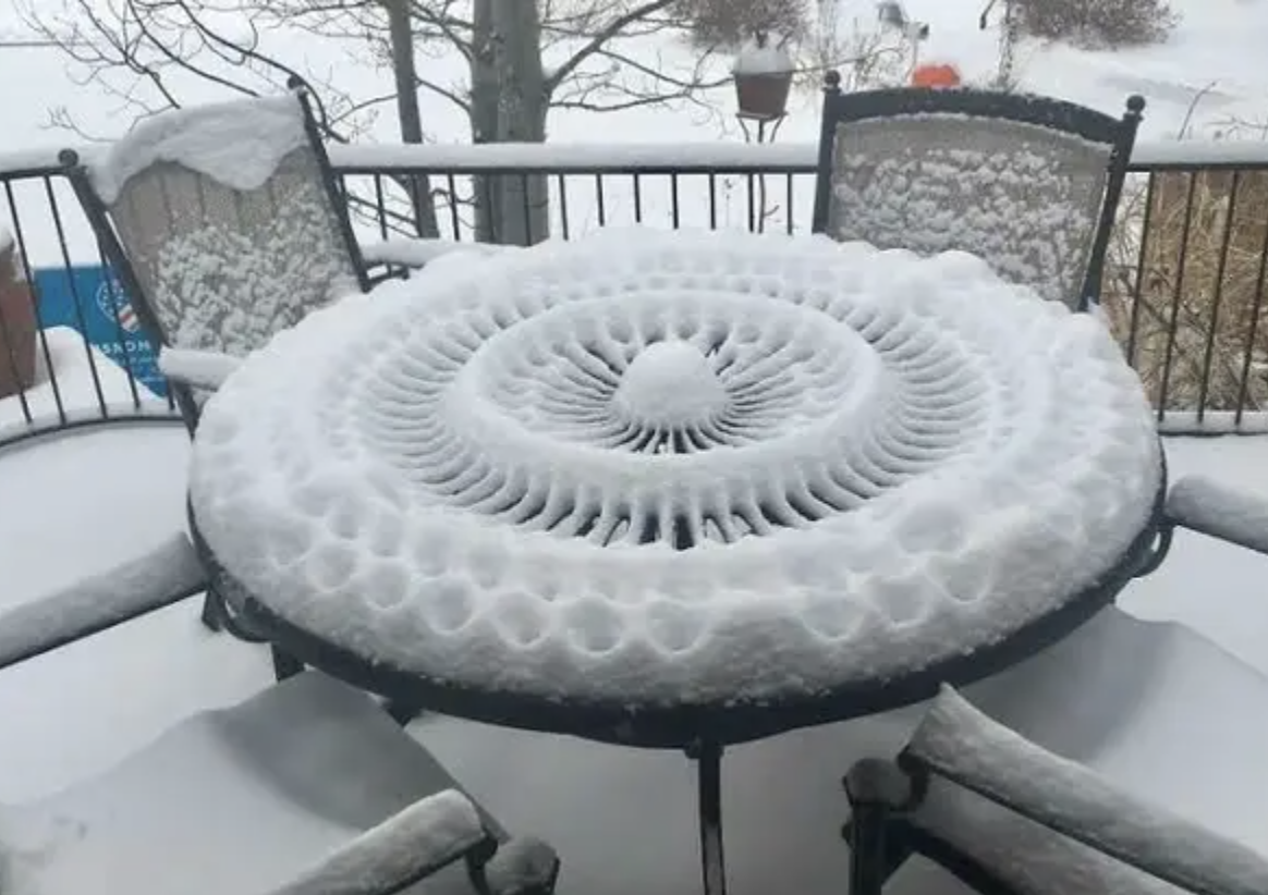 A round table outside with symmetrical snow patterns, resembling a flower