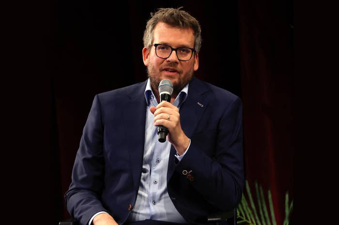 John Green in a suit speaking into a microphone on stage