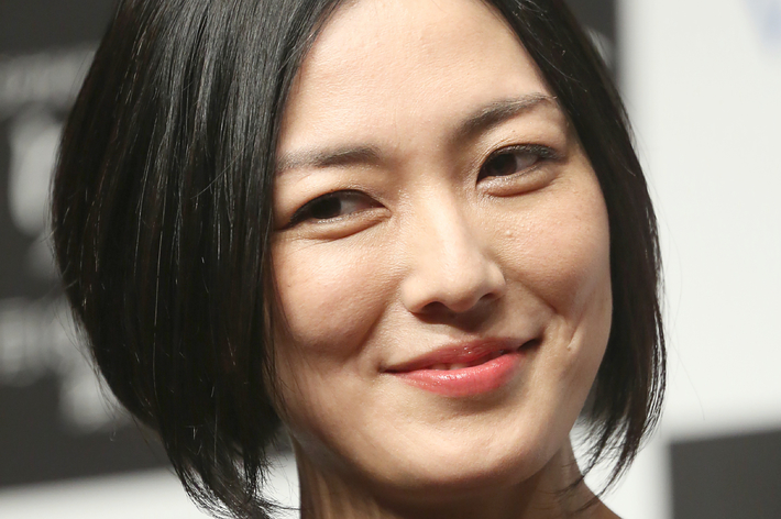 写真は笑顔の女性がカメラを見ている様子です。