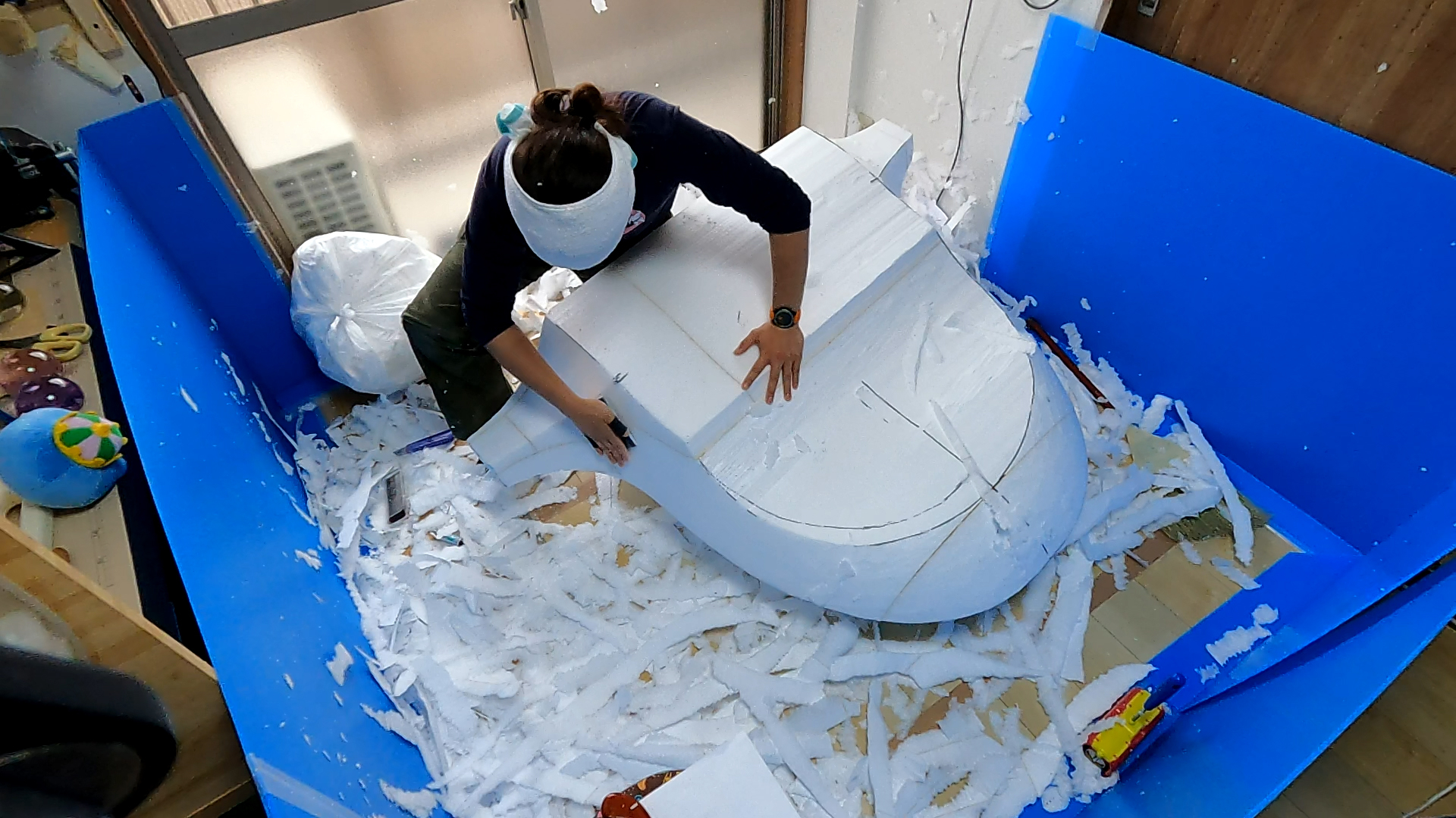 立方体の青いスペースにいる人が大きな紙の彫刻を作成中です。