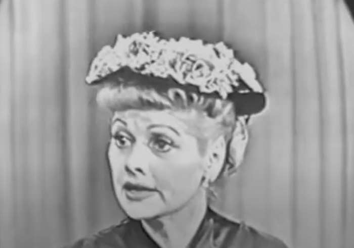 Lucille Ball wearing a floral hat and vintage hairstyle in a still from a classic TV show