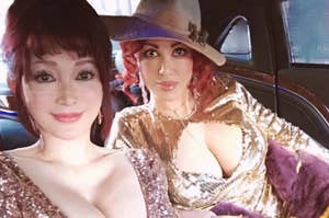 二人の女性が車内でセルフィーを撮っています。左は金色のドレス、右は紫の帽子をかぶっています。