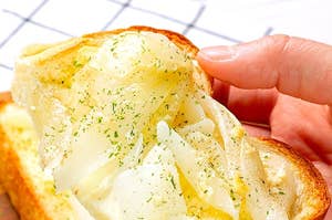 手に持たれたトーストに玉ねぎとチーズがのっている。