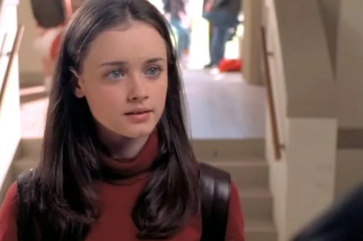 Rory Gilmore of Gilmore Girls in a school hallway wearing a turtleneck and backpack