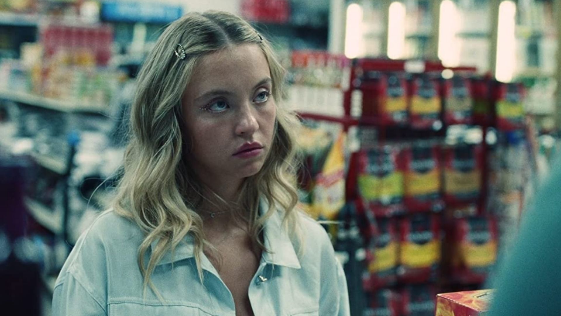 Woman portrayed by Sydney Sweeney looks pensive in a grocery store aisle