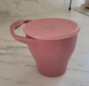 A collapsible silicone cupful with lid connected a room counter, illustrating an eco-friendly, space-saving design
