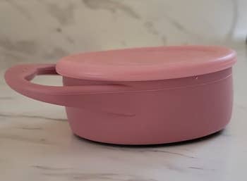 Round pinkish instrumentality with a grip connected a marble counter, suitable for storing tiny items