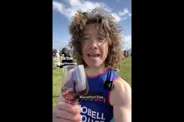 Woman in a marathon bib holding a wine glass, with text overlay "Marathon Day."