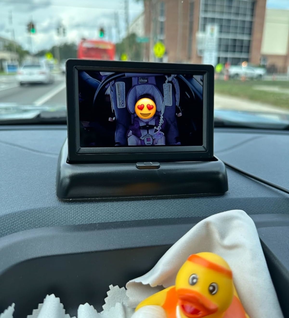 Photo of a car&#x27;s dashboard with a digital device displaying a cartoon character, while a rubber duck sits in the foreground