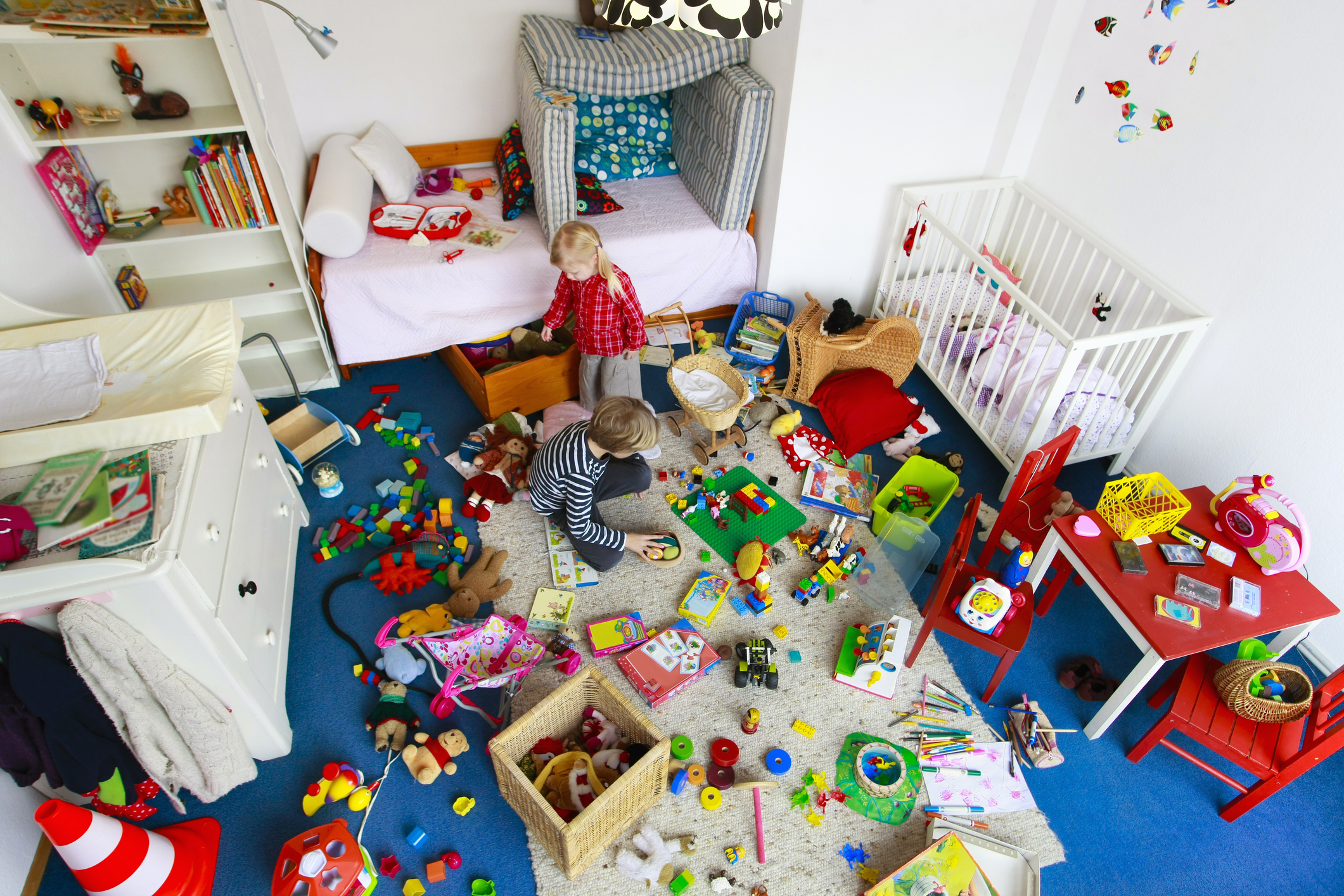 Two young children play in a cluttered room filled with toys, signaling a lively playtime environment