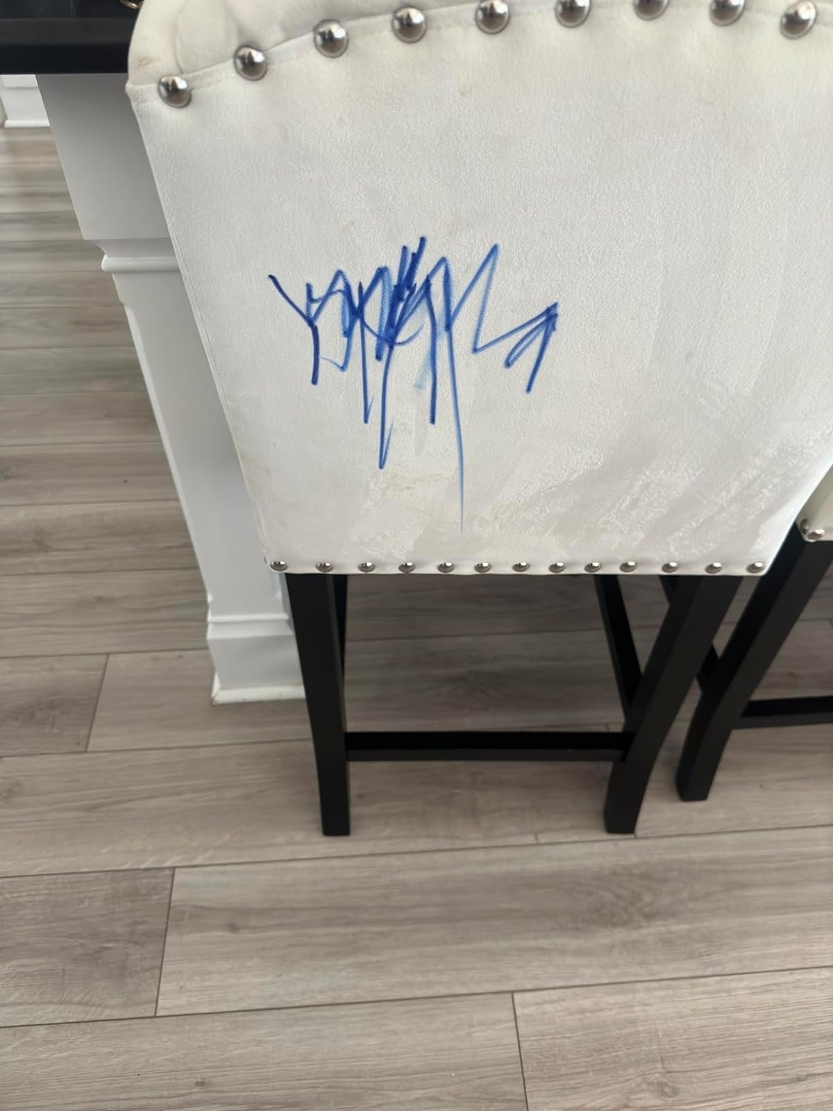 A white chair with studded detailing and a blue signature on the backrest