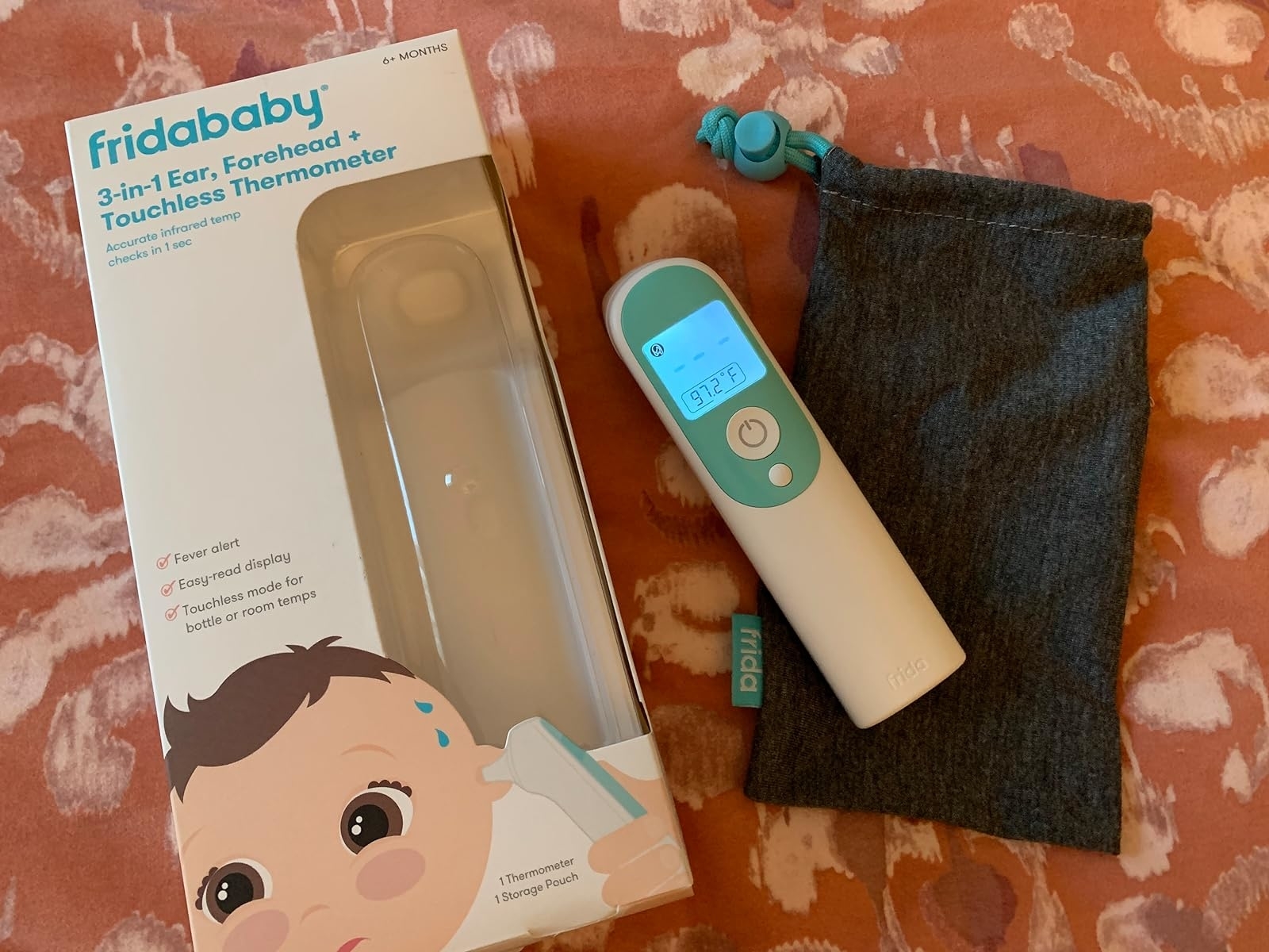 3-in-1 ear, forehead, touchless thermometer by Fridababy with packaging, a carrying pouch, and a displayed temperature reading