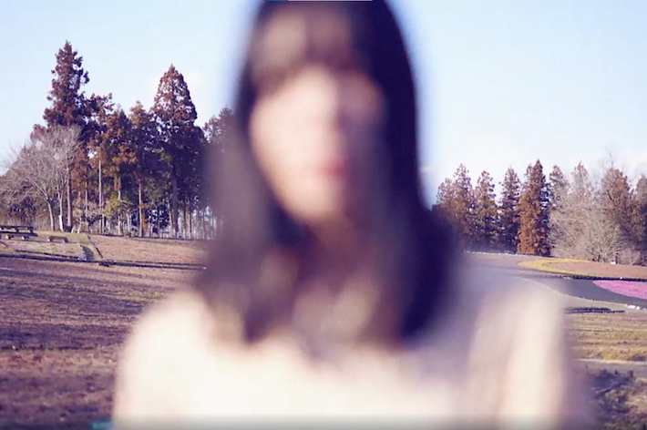 ピンボケの女性の顔、背景に木々と草原