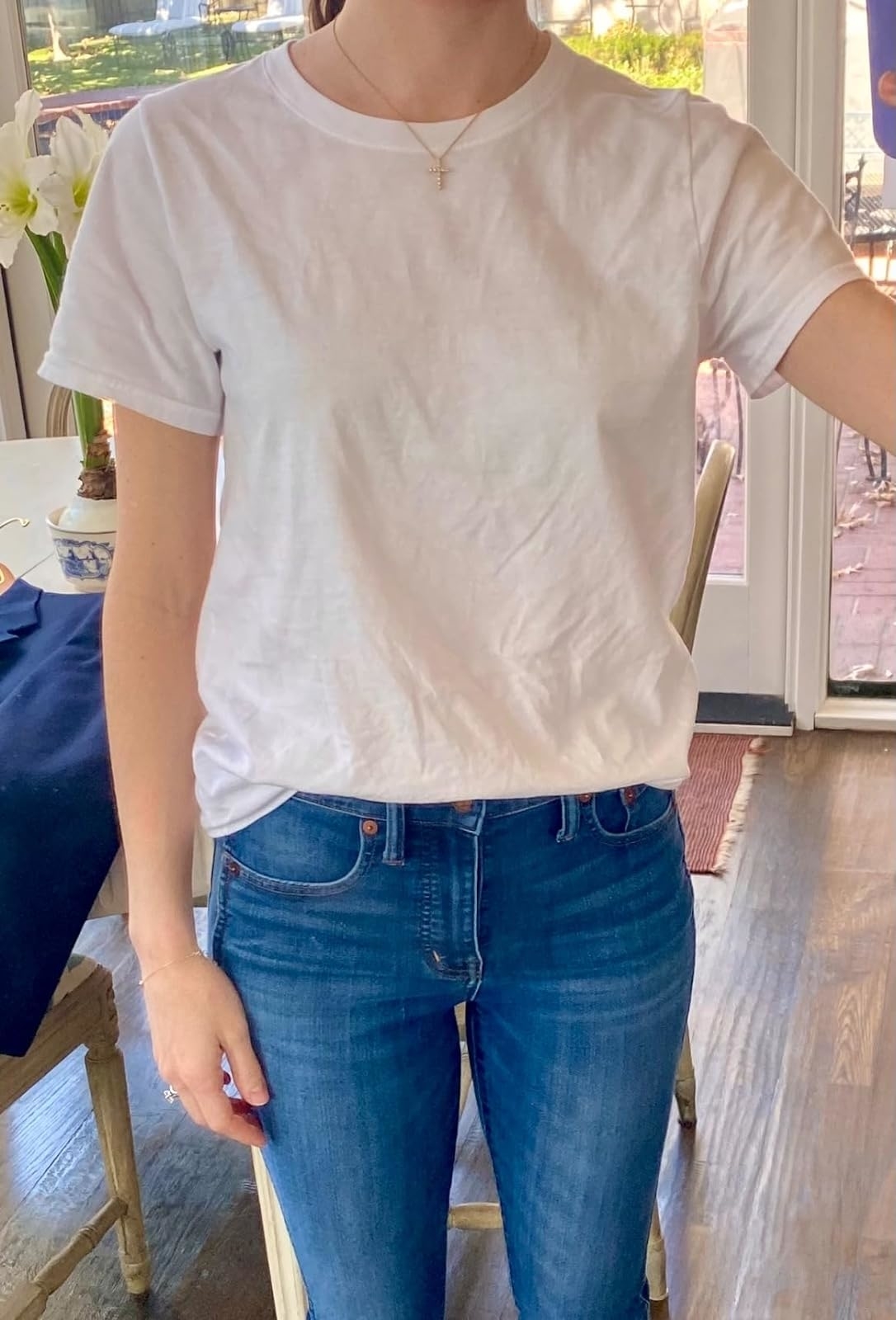 Person in a casual white t-shirt and blue jeans standing indoors