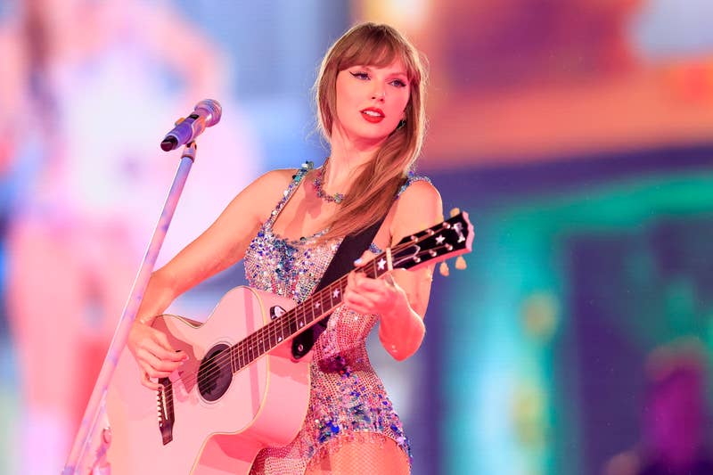 Taylor Swift performing with a guitar, wearing a sparkling dress